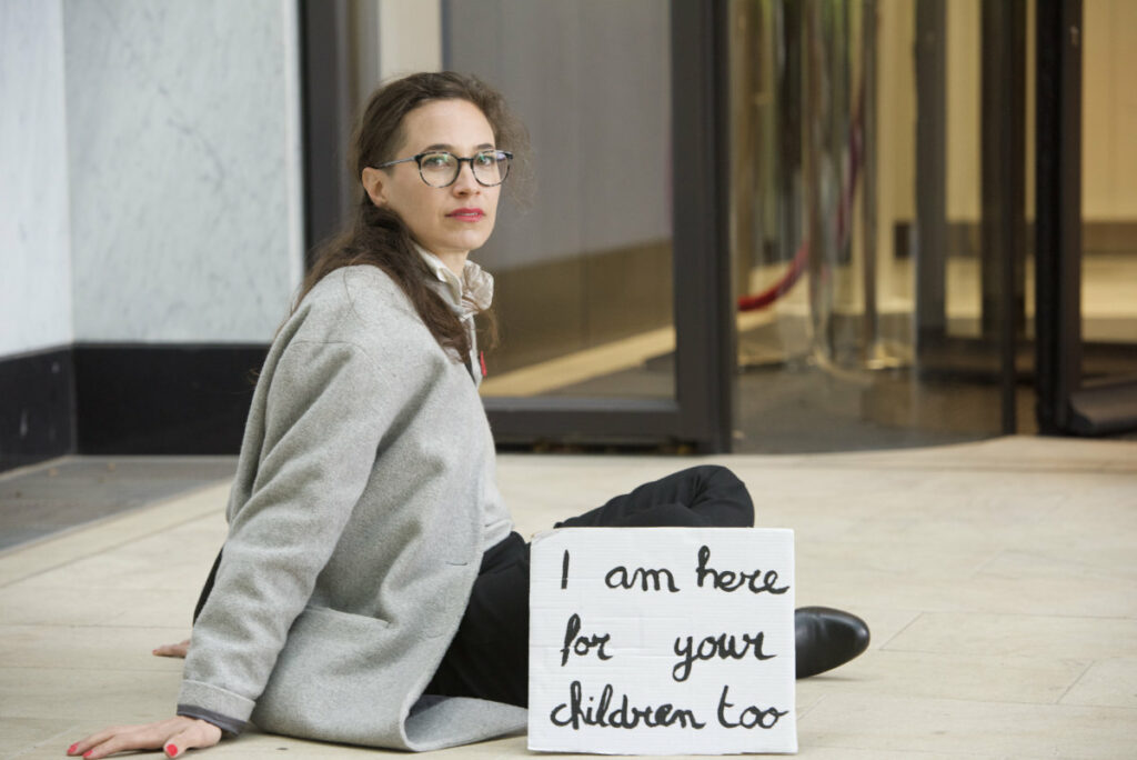 Activist glued on the floor with a banner saying 'I'm here for your children too'