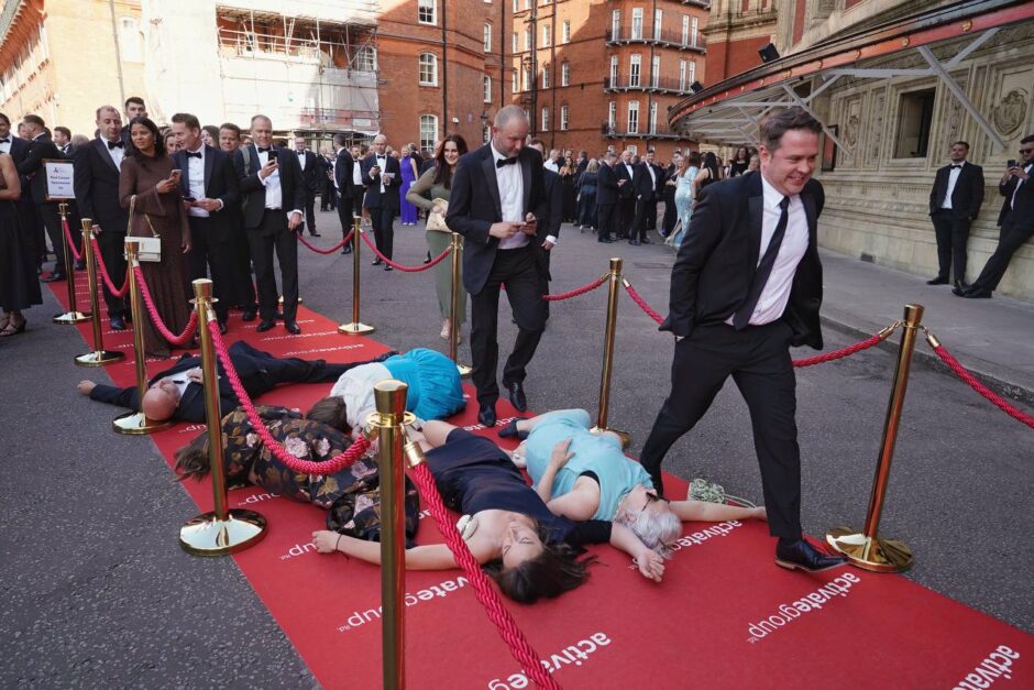 Ceremony attendees step over rebel 'die-in' on the red carpet